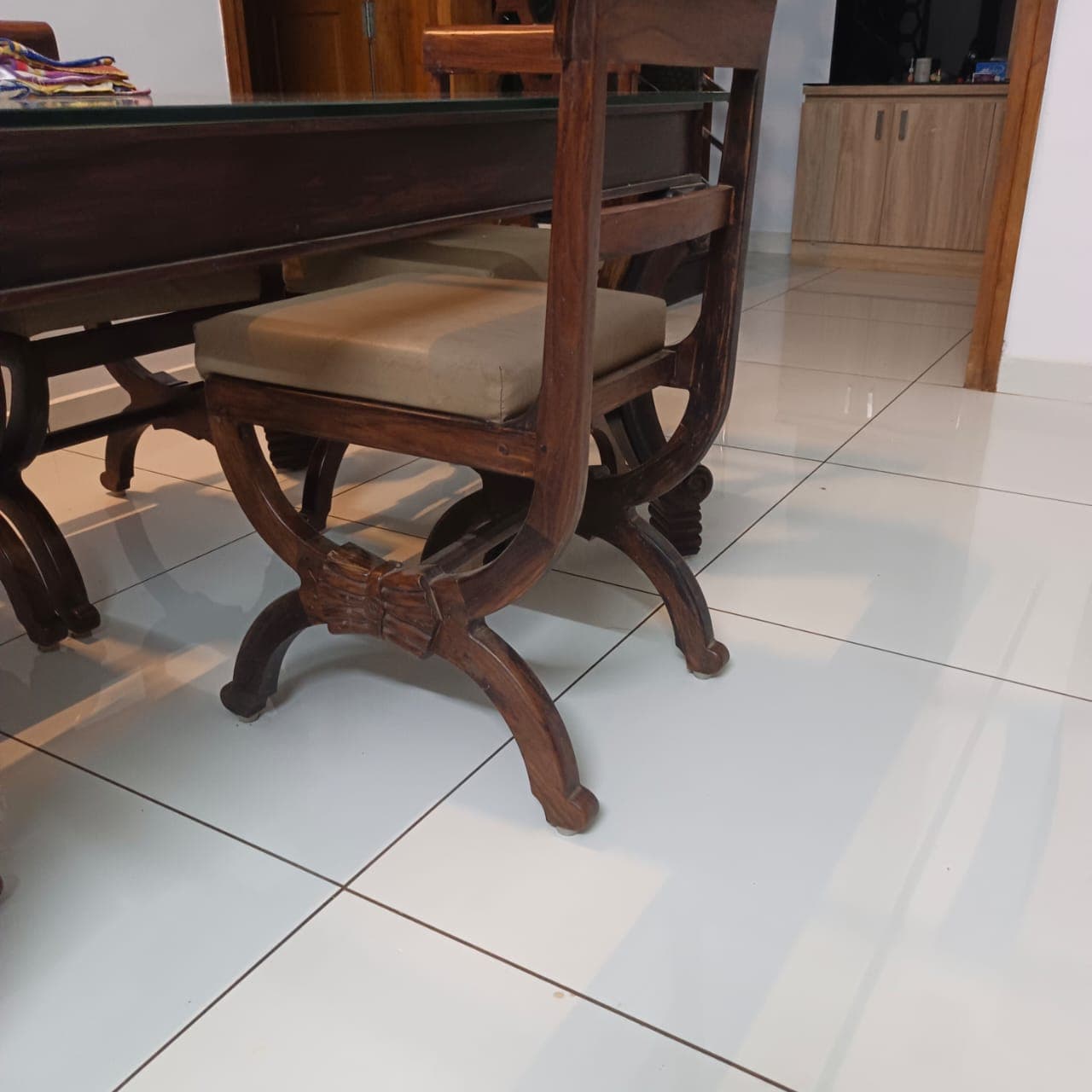Polished wooden dining chair with crossed curved legs, carved centre detail and upholstered seat
