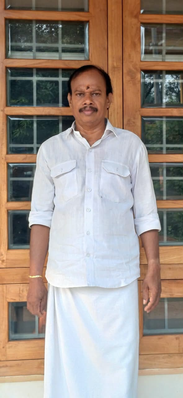 Sivadasan, founder of Decorators India, standing in front of teak-framed glass doors