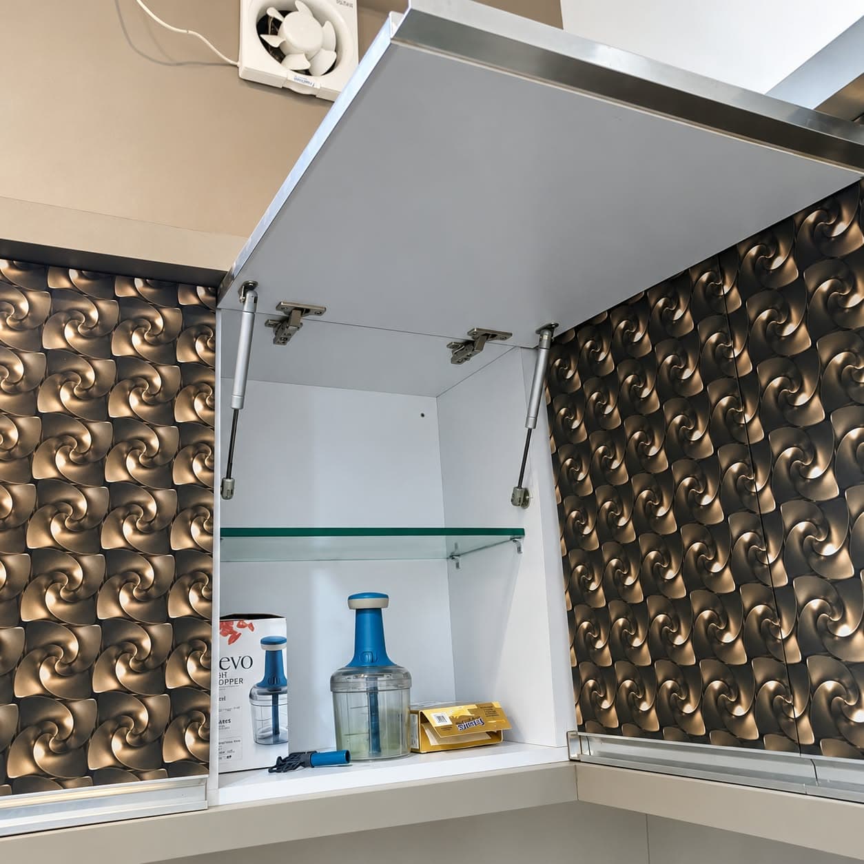 Open lift-up kitchen wall cabinet with gas struts, white carcass and glass shelf between bronze 3D laminate shutters